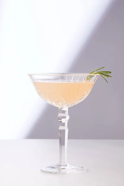 Алкогольний коктейль у склянці з розмарином на білому столі — стокове фото