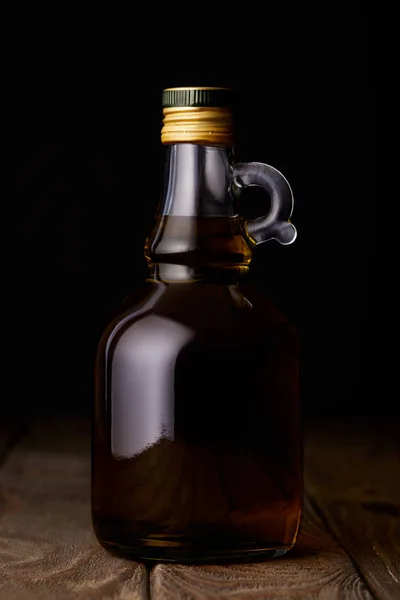 Bottiglia di olio su tavola di legno su fondo nero — Foto stock
