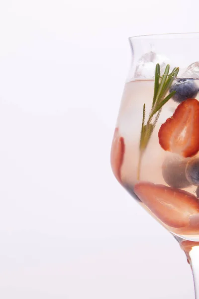 Partial view of glass of lemonade with rosemary, blueberries and strawberries isolated on white background — Stock Photo