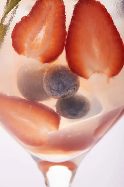 Close up shot of glass of lemonade with rosemary, blueberries and strawberries — Stock Photo