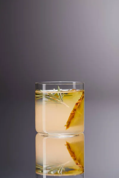 Glass of fresh pineapple cocktail on reflective surface and on grey — Stock Photo