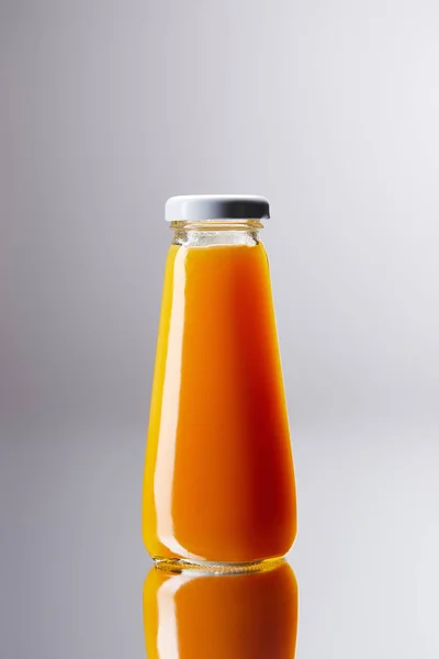 Garrafa de suco de laranja fresco na superfície reflexiva — Fotografia de Stock