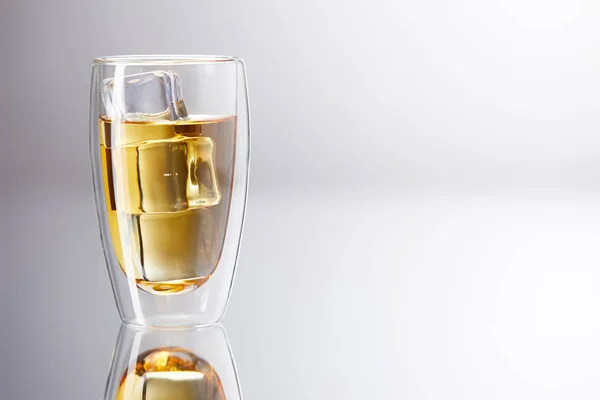 Bicchiere di whisky con cubetti di ghiaccio sulla superficie riflettente — Foto stock
