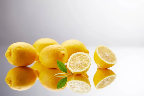 Nahaufnahme eines Bündels frischer Zitronen auf reflektierender Oberfläche und auf grau — Stockfoto