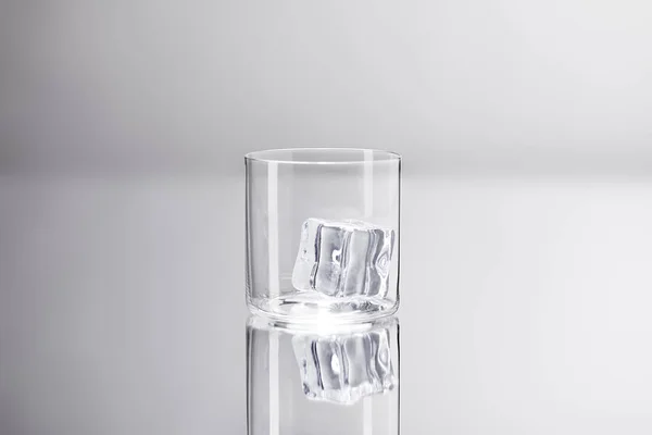 Glas mit Eiswürfel auf reflektierender Oberfläche — Stockfoto