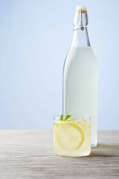 Бутылка и стакан свежей итальянской лимончелло на деревянной поверхности — стоковое фото