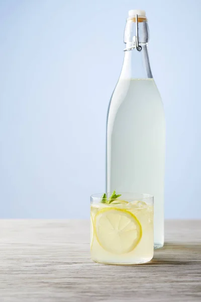 Garrafa e vidro de limoncello italiano fresco na superfície de madeira — Fotografia de Stock