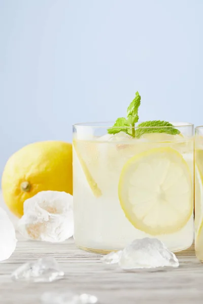 Bicchieri freschi di limonata con ghiaccio e limone sulla superficie di legno — Foto stock