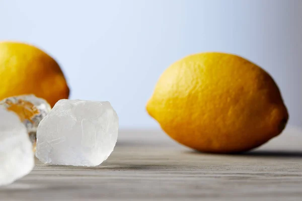 Primo piano di limoni e cubetti di ghiaccio sulla superficie di legno — Foto stock