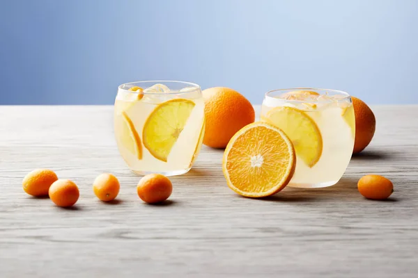 Glasses of delicious lemonade with ripe oranges on wooden tabletop — Stock Photo