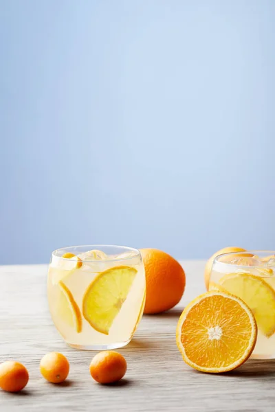 Glasses of cooled delicious lemonade with ripe oranges on wooden tabletop — Stock Photo