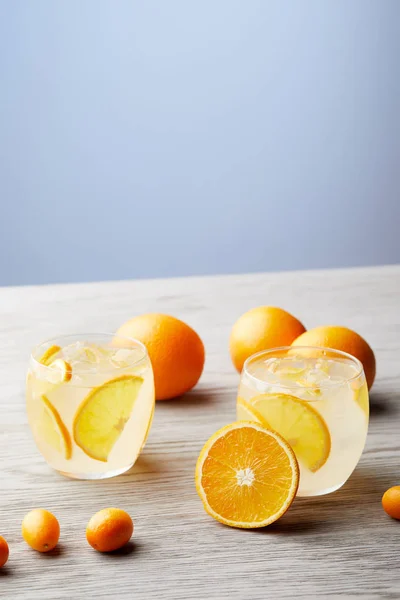 Стаканы свежего лимонада со спелыми апельсинами на деревянном столе — стоковое фото