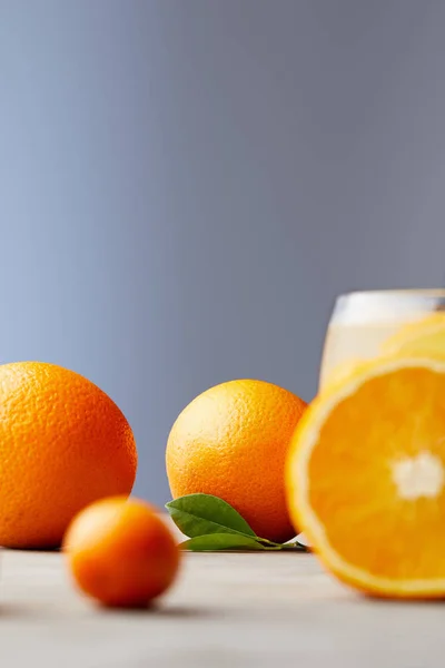 Ripe oranges and glass of juice on wooden surface — Stock Photo