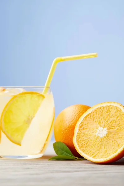 Стакан вкусного лимонада с апельсинами на деревянном столе — стоковое фото