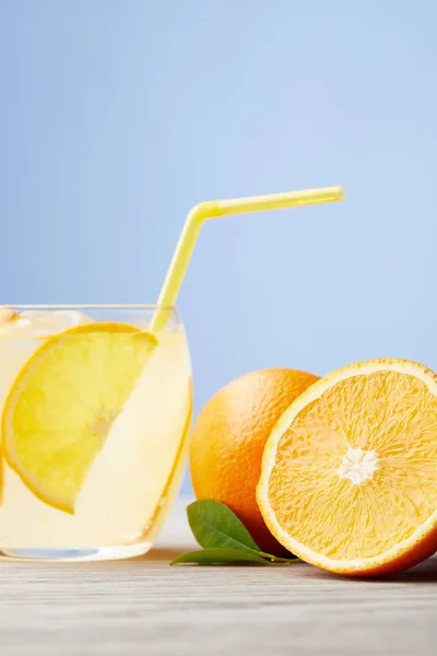 Glass of delicious lemonade with oranges on wooden table — Stock Photo