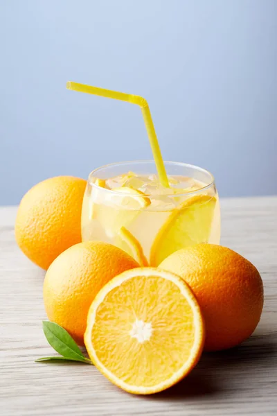 Glass of lemonade with oranges on wooden table — Stock Photo