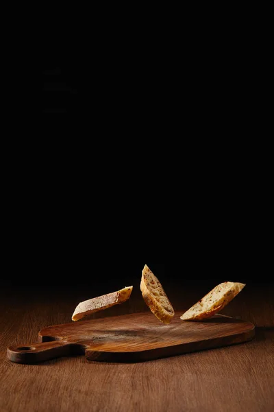 Slices of wholegrain bread falling on wooden table surface — Stock Photo