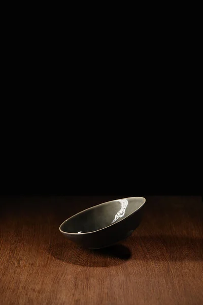 Empty ceramic bowl flying above wooden table surface — Stock Photo