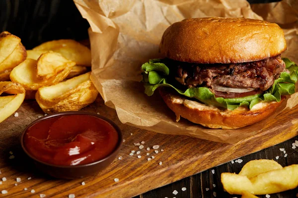 Гамбургер и картофель фри подаются на деревянной доске с соусом — стоковое фото