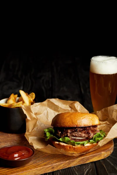 Hambúrguer e batatas fritas servidos com cerveja gelada em vidro — Fotografia de Stock