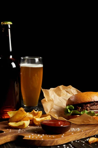 Hamburger and french fries served with cold beer on wooden board — Stock Photo