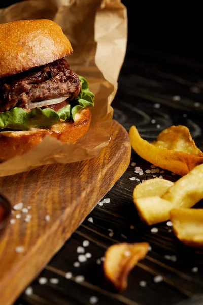 Jantar de fast food tentador com batatas fritas douradas e hambúrguer na mesa de madeira — Fotografia de Stock