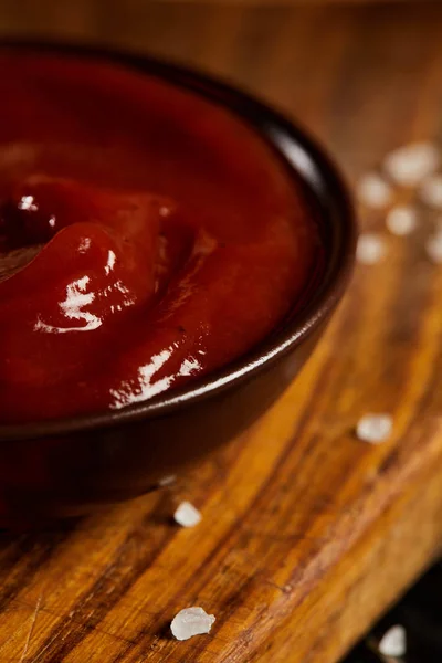 Ketchup en platillo servido sobre tabla de madera con sal - foto de stock