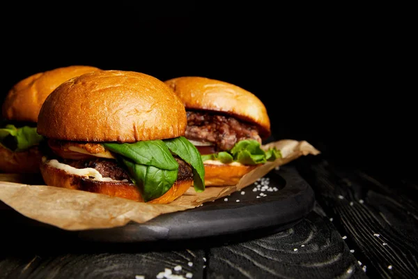 Conjunto de junk food com deliciosos hambúrgueres quentes em tábua de madeira — Fotografia de Stock