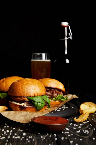 Set of junk food hamburgers on table with beer in bottle and glass — Stock Photo