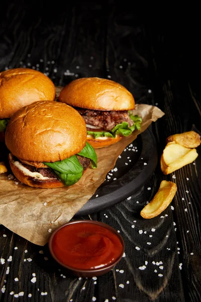 Tempting fast food diner with hamburgers and potatoes on wooden table — Stock Photo