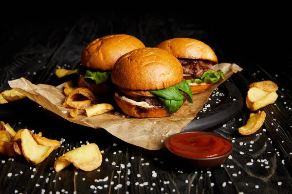 Leckere Hamburger und Pommes mit Ketchup auf Holzbrett — Stockfoto