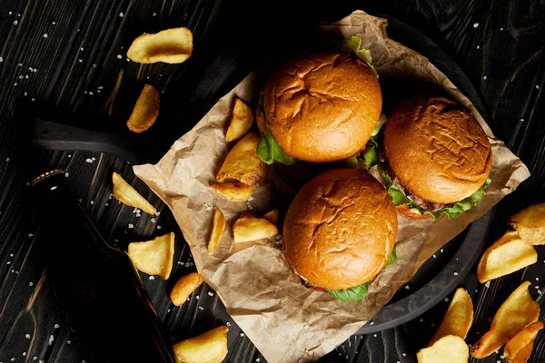 Вид сверху на гамбургеры и фри, подаваемые на ремесленной бумаге — стоковое фото