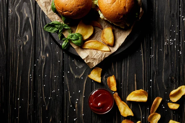Top view composition of hamburgers and fried potatoes on wooden table — Stock Photo