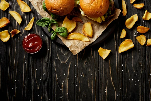 Vista superior de hambúrgueres tentadores e batatas fritas na mesa de madeira — Fotografia de Stock