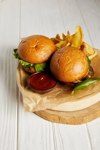 Гамбургеры и картофель фри с кетчупом подаются на бумаге на белом столе — стоковое фото