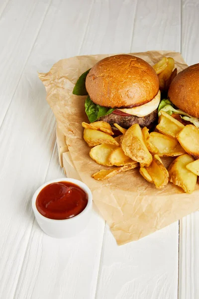 Tentador restaurante de comida rápida con hamburguesas y papas fritas servidas en mesa blanca - foto de stock