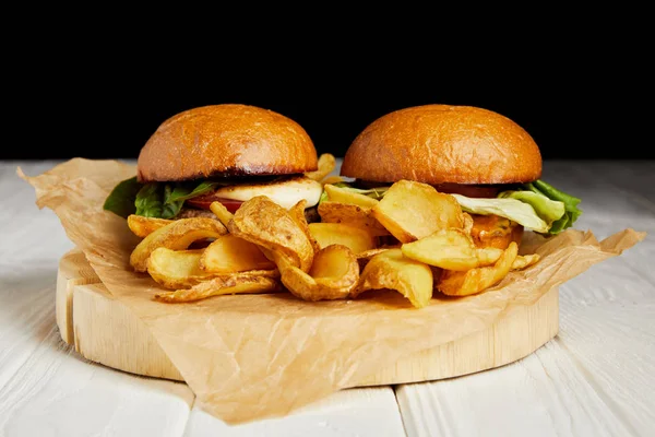 Hambúrgueres e batatas fritas servidos em papel artesanal sobre mesa branca — Fotografia de Stock
