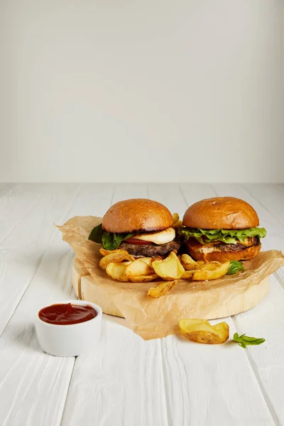 Tempting fast food diner with hamburgers and golden potatoes served with sauce on table — Stock Photo