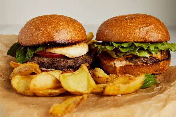 Concepto de comida chatarra con hamburguesas y papas fritas sobre papel artesanal - foto de stock
