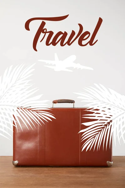 Vintage brown leather suitcase with palm leaves, airplane and travel lettering — Stock Photo