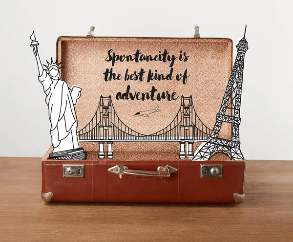 Bolsa de viaje vintage abierta con ilustración y letras - La espontaneidad es el mejor tipo de aventura - foto de stock