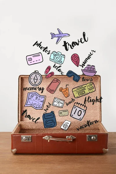 Open vintage suitcase with travel icons — Stock Photo