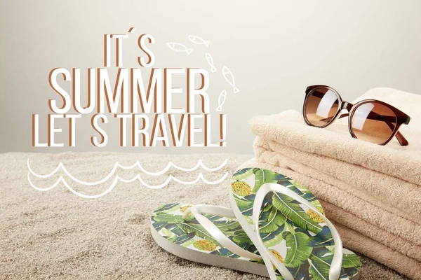 Vue rapprochée de la pile de serviettes, lunettes de soleil et tongs d'été sur sable sur fond gris avec inspection 