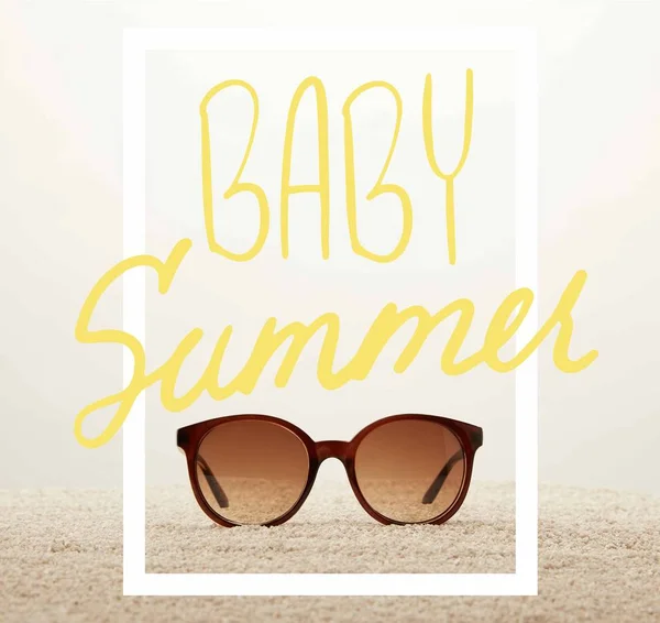 Close up view of sunglasses on sand on grey background with 