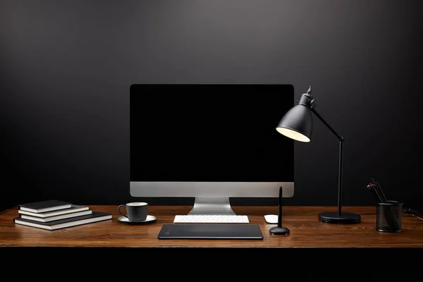 Vista de primer plano del lugar de trabajo del diseñador gráfico con tableta gráfica, pantalla de computadora en blanco, cuadernos y taza de café en la mesa de madera — Stock Photo
