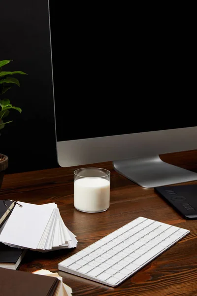 Vista de cerca del lugar de trabajo de diseño con vaso de leche, pantalla de computadora y teclado en la mesa de madera — Stock Photo