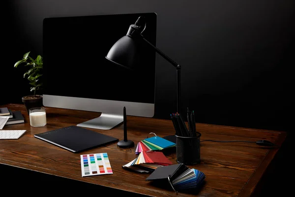 Крупный план графического дизайнера рабочего места с красочным поддоном, графическим планшетом, экраном компьютера и лампой на деревянной поверхности — стоковое фото