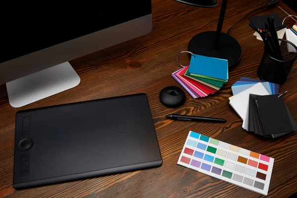 Vista de cerca del lugar de trabajo de diseñador gráfico con paleta de colores, pantalla de computadora y tableta gráfica en la superficie de madera — Stock Photo