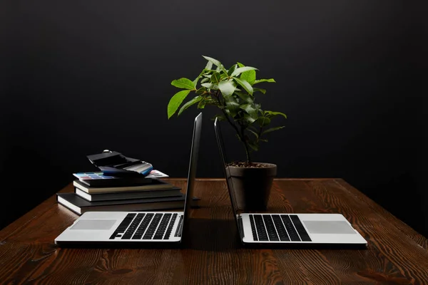 Vista ravvicinata del luogo di lavoro del progettista con i computer portatili, notebook e pallet sul tavolo di legno sullo sfondo della parete nera — Foto stock