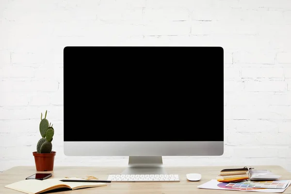 Vista cercana del lugar de trabajo del diseñador con el cuaderno, la pantalla del ordenador en blanco, el teclado y la plataforma en la mesa de madera - foto de stock